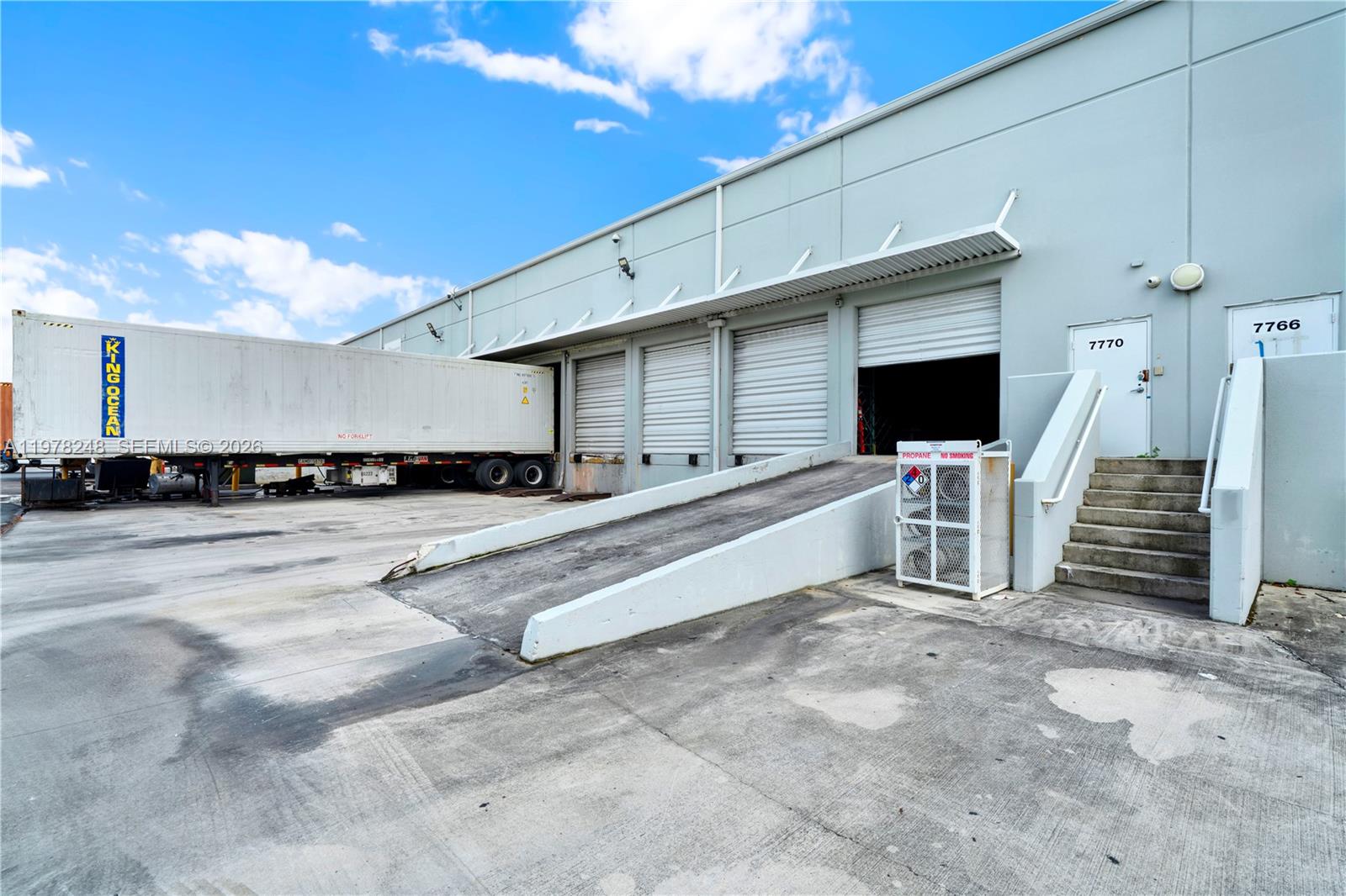 An exterior view of a warehouse building featuring loading docks, a ramp, and stairs — 7770 NW 46th St # 23, Doral FL 33166, DORAL, FL