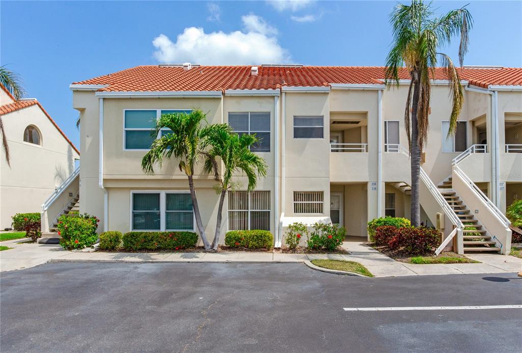 A two-story residential building with a tiled roof, palm trees, and an exterior staircase — 6171 BAHIA DEL MAR BOULEVARD UNIT 216, ST PETERSBURG, FL