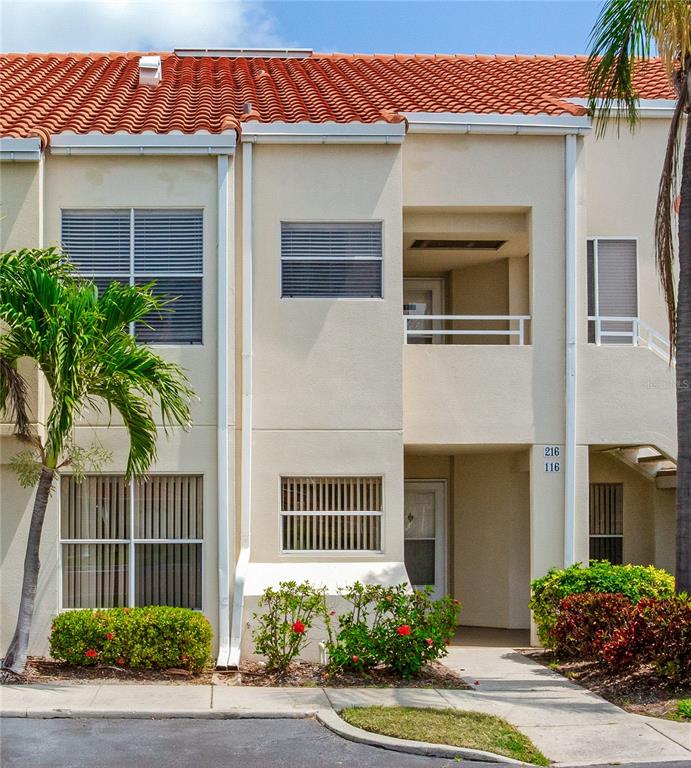 A two-story stucco townhouse features a red tile roof and a small ground-level patio — 6171 BAHIA DEL MAR BOULEVARD UNIT 216, ST PETERSBURG, FL