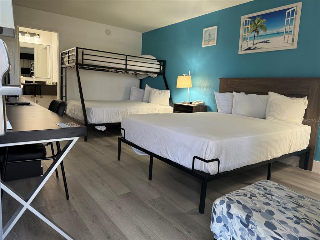 A hotel room features a queen bed, a bunk bed, a desk, and a bathroom entrance — 7150 N TAMIAMI TRAIL UNIT S512, SARASOTA, FL