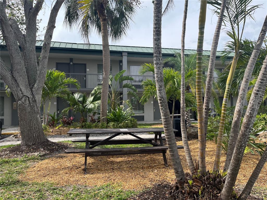 A wooden picnic table sits on a mulch-covered area in front of a two-story hotel building — 7150 N TAMIAMI TRAIL UNIT S512, SARASOTA, FL