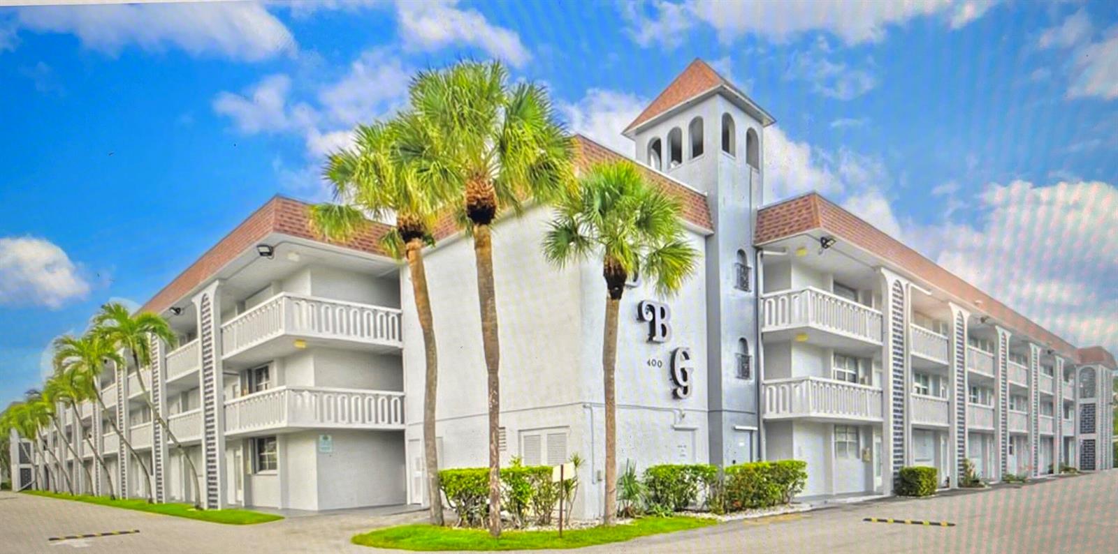 A three-story apartment building with white stucco walls, a brown roof, and palm trees — 400 SE 10th Street # 308, Deerfield Beach FL 33441, DEERFIELD BEACH, FL