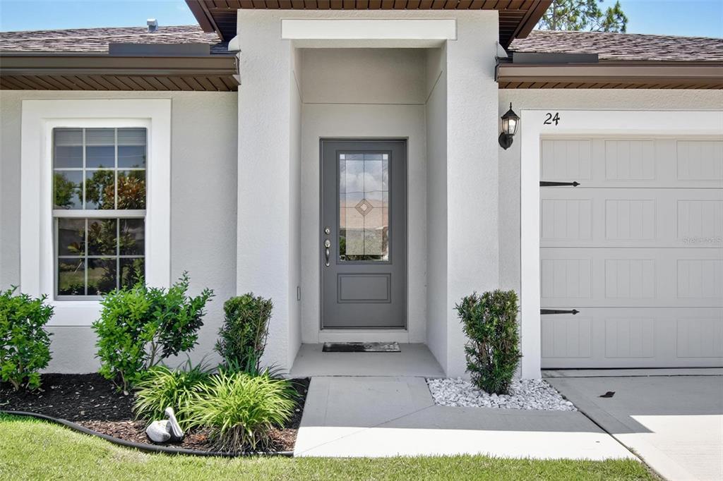 The exterior of a house features a gray front door, a window, and a garage — 24 PERKINS LANE, PALM COAST, FL