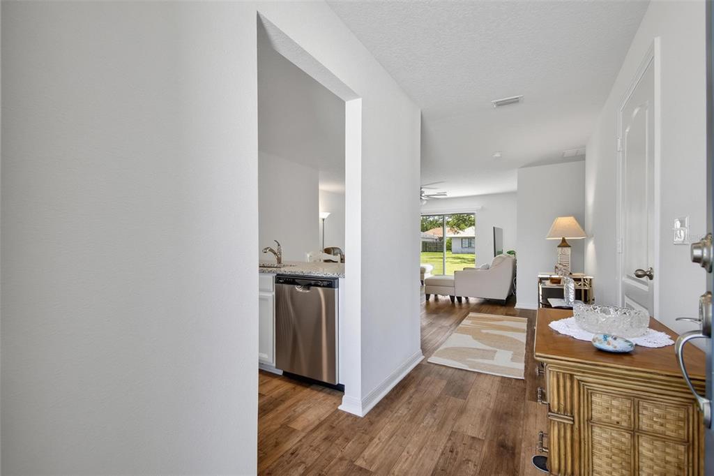 A view from an entryway looking into a kitchen and a living room with flooring — 24 PERKINS LANE, PALM COAST, FL