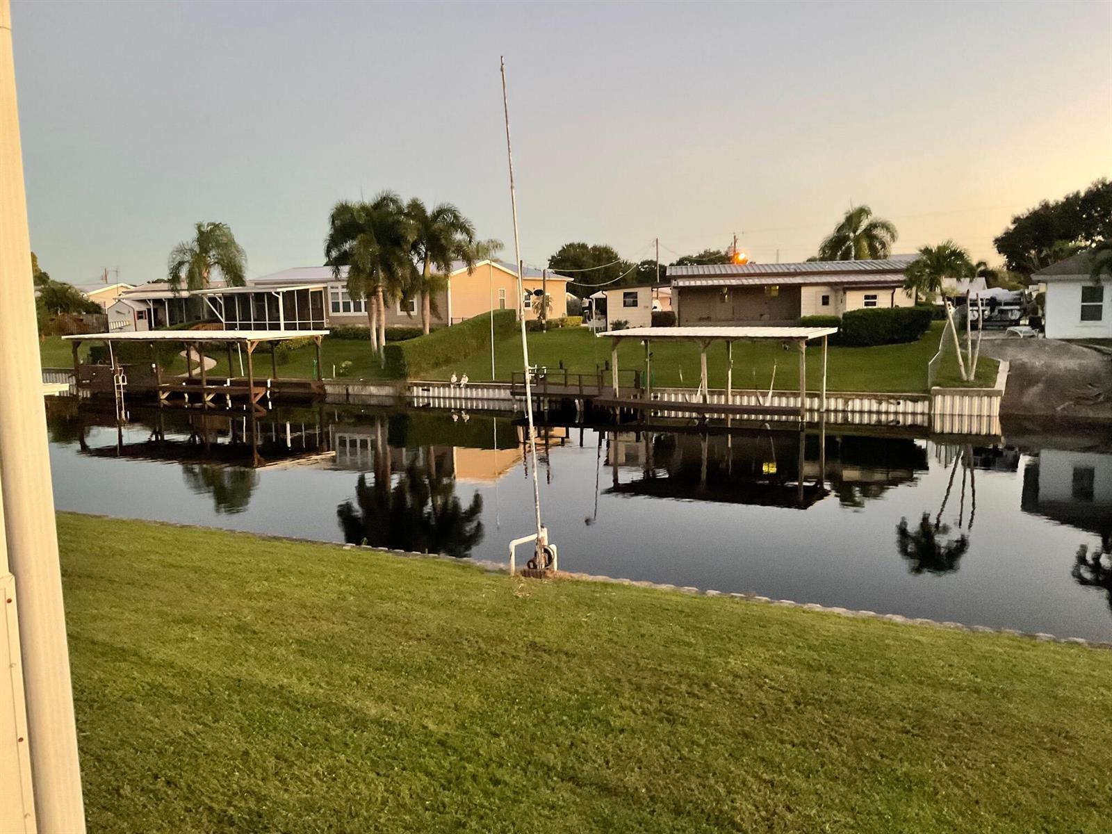 A canal view featuring boat docks, grassy lawns, and houses under a clear evening sky — 2508 SE 32nd Street, Okeechobee FL 34974, OKEECHOBEE, FL