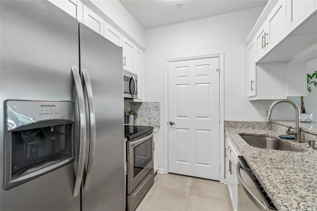 A kitchen features stainless steel appliances, white cabinetry, and granite countertops — 800 S DAKOTA AVENUE UNIT 237, TAMPA, FL