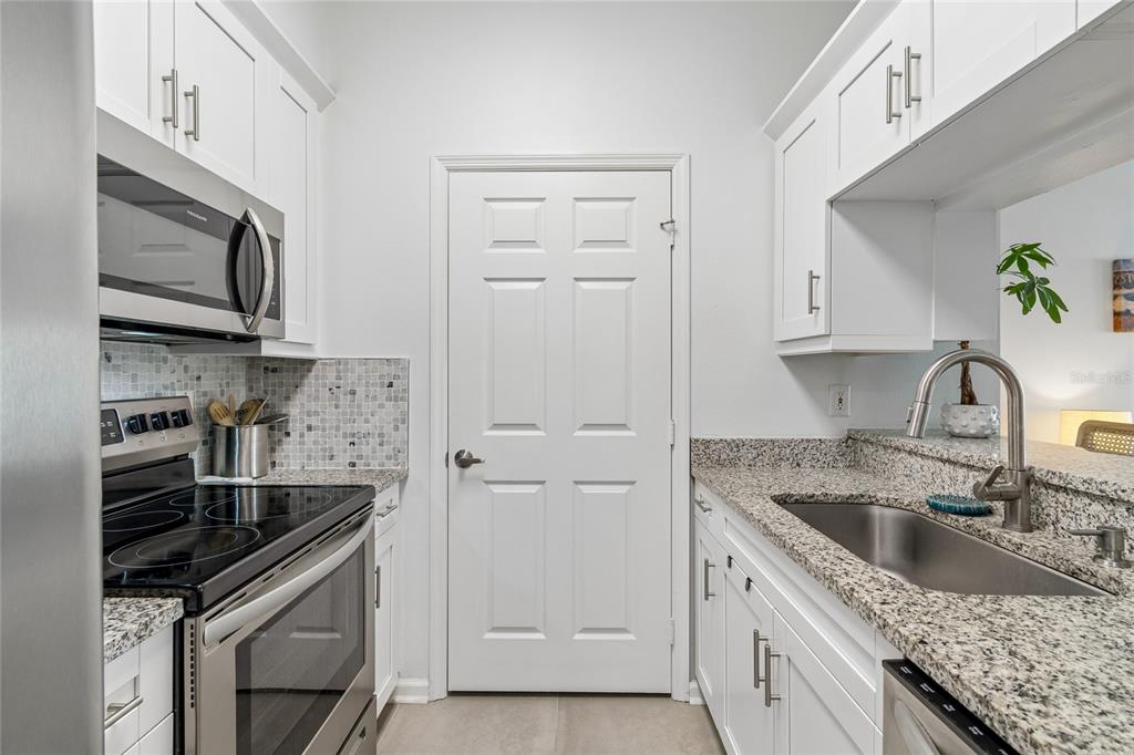A galley kitchen features white cabinets, granite countertops, stainless steel appliances, and a central door — 800 S DAKOTA AVENUE UNIT 237, TAMPA, FL