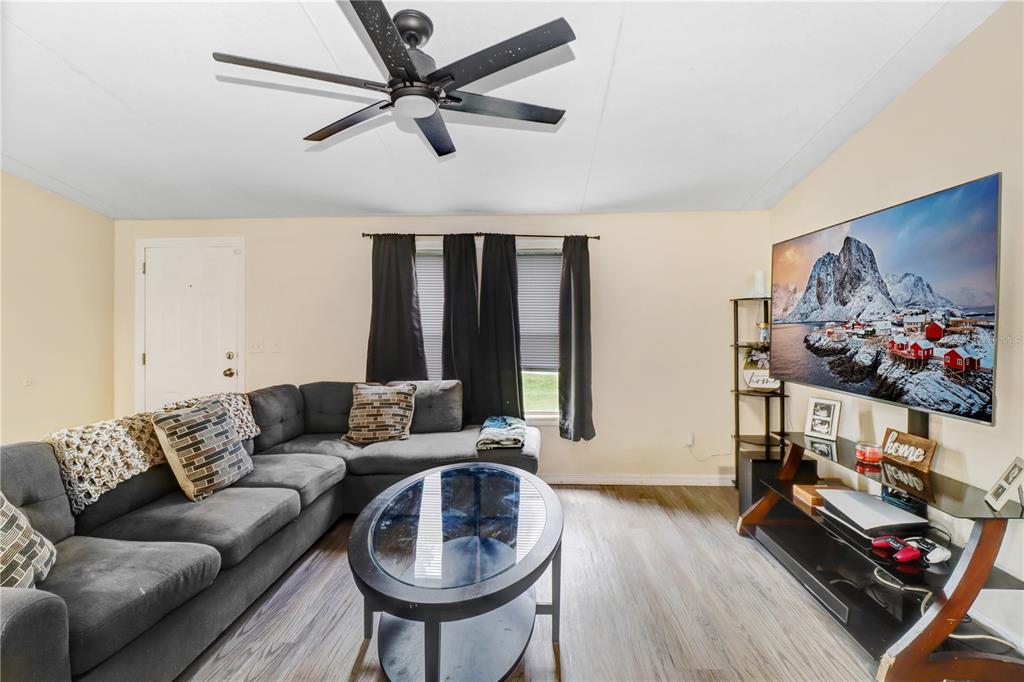 A living room features a grey sectional sofa, a glass coffee table, and a wall-mounted television — 1135 DEAN STREET, MULBERRY, FL