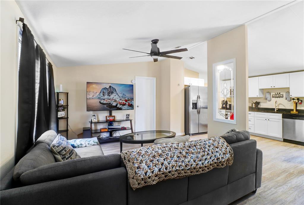 A living room with a grey sectional sofa faces a television and an open kitchen — 1135 DEAN STREET, MULBERRY, FL