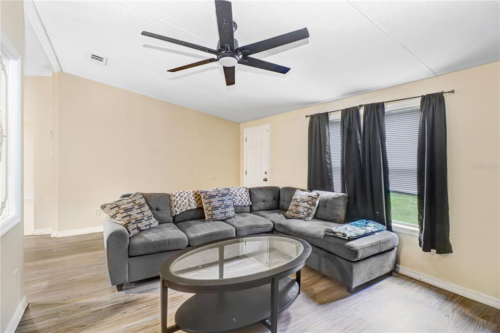 A living room features a gray sectional sofa, a glass coffee table, and a ceiling fan — 1135 DEAN STREET, MULBERRY, FL