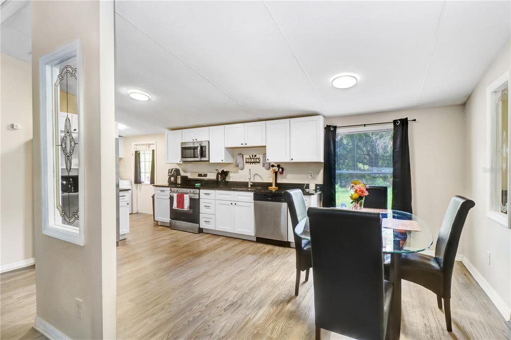 A kitchen with white cabinets and stainless steel appliances opens into a dining area — 1135 DEAN STREET, MULBERRY, FL