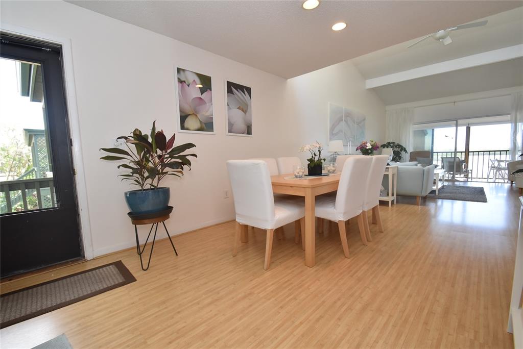 A dining area with a light wood table, white chairs, and bamboo flooring — 1512 PELICAN POINT DRIVE UNIT BA264, SARASOTA, FL