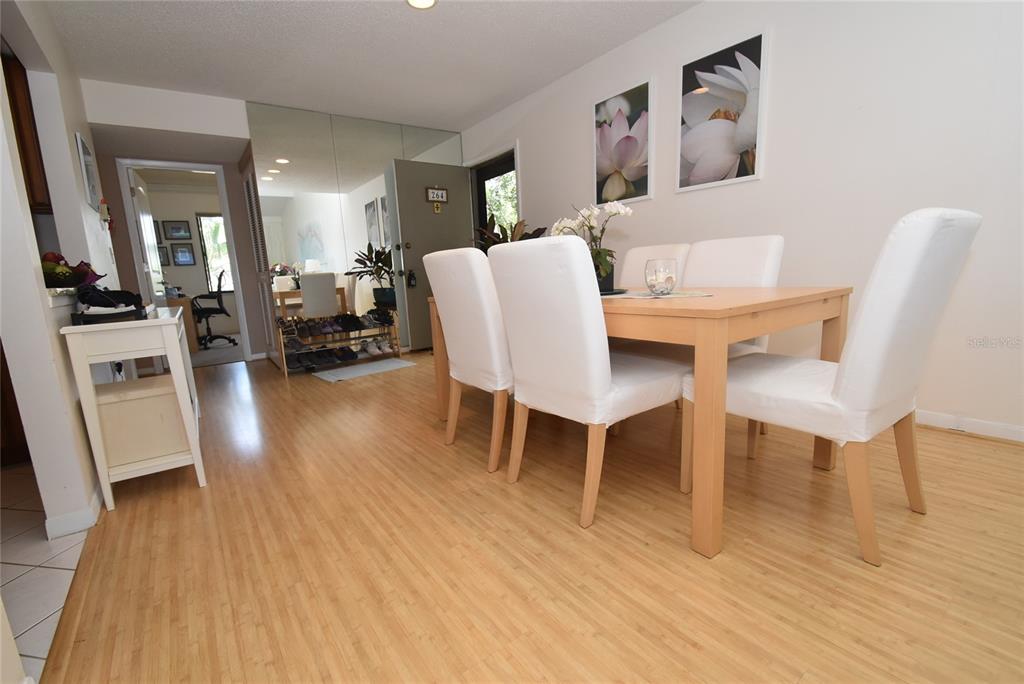 A dining area features a light wood table, white chairs, and light wood flooring — 1512 PELICAN POINT DRIVE UNIT BA264, SARASOTA, FL
