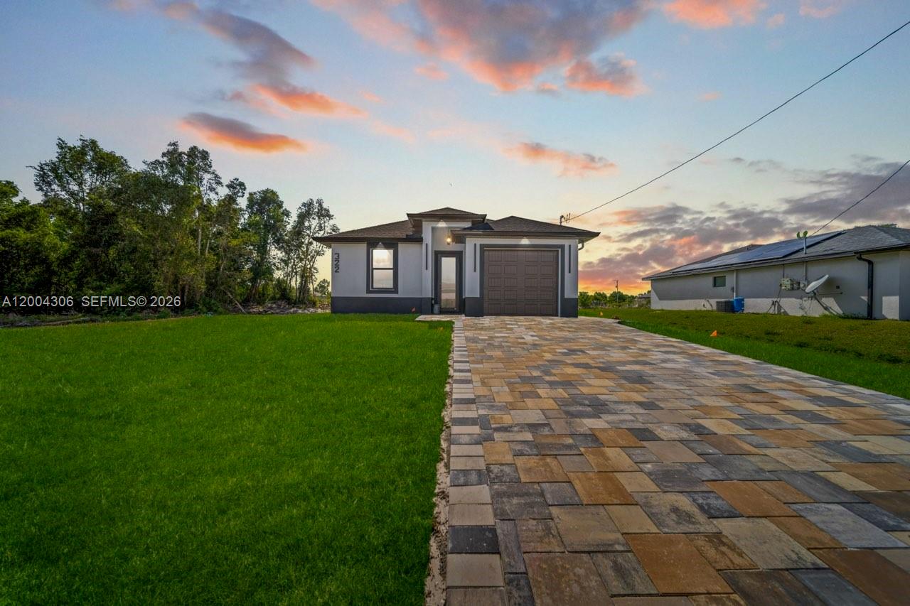 A single-story house with a paved driveway and a garage at sunset — 322 Ranch Ave, Lehigh Acres FL 33974, LEHIGH ACRES, FL