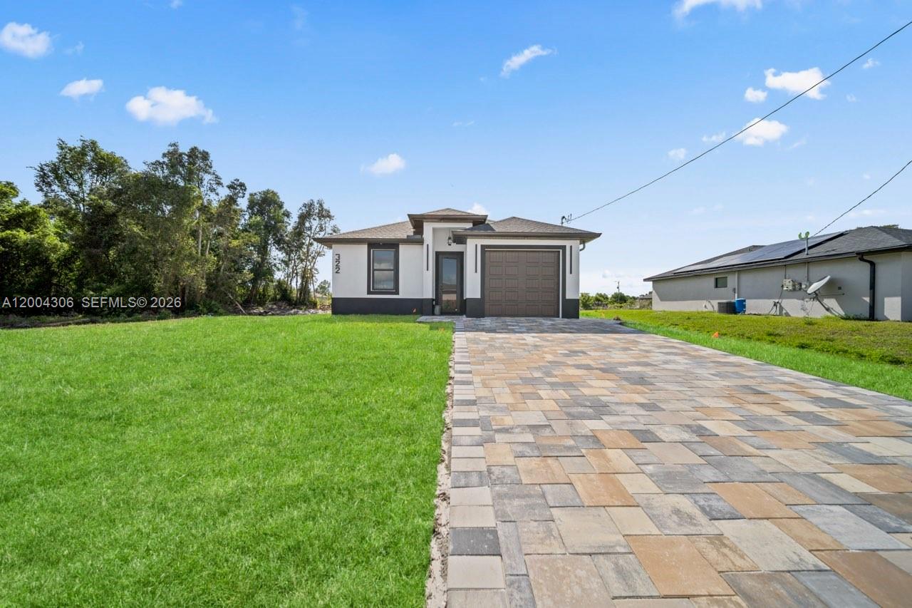 A single-story house with a paved driveway and a brown garage door stands on grass — 322 Ranch Ave, Lehigh Acres FL 33974, LEHIGH ACRES, FL