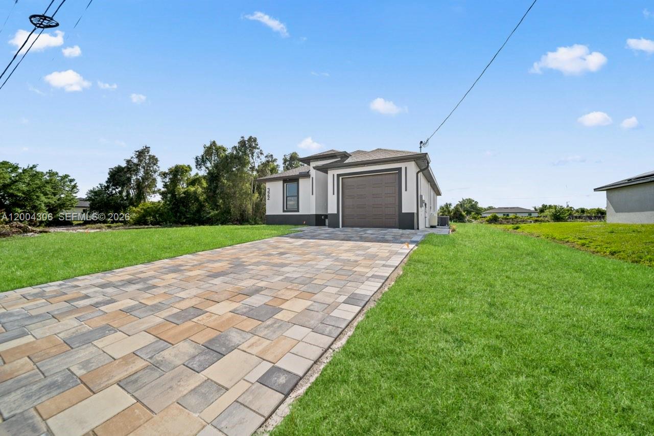 A single-story house with a paved driveway and a brown garage door under a blue sky — 322 Ranch Ave, Lehigh Acres FL 33974, LEHIGH ACRES, FL