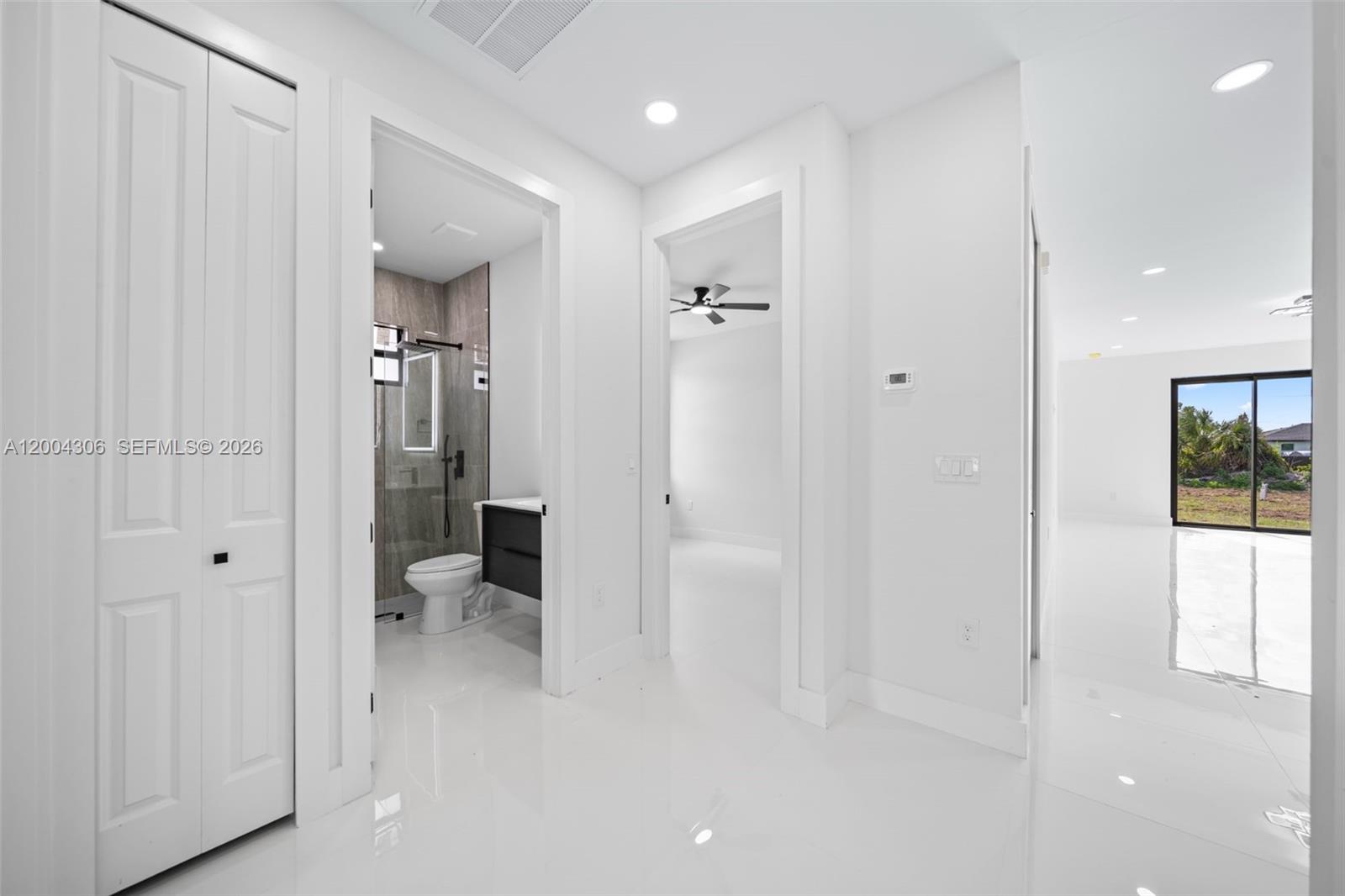 A bright hallway leads to a bathroom, a bedroom, and a living area with sliding doors — 322 Ranch Ave, Lehigh Acres FL 33974, LEHIGH ACRES, FL
