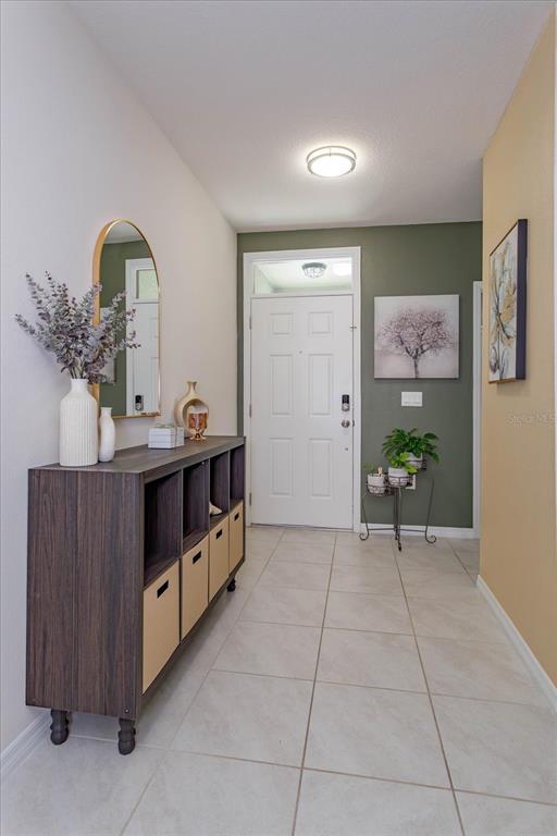 An entryway features a dark wood storage unit, an arched mirror, and a white door — 1287 BERRY LANE, DAVENPORT, FL