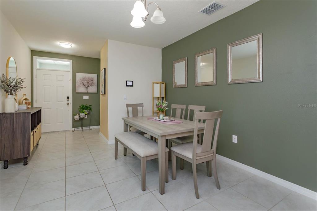 A dining area features a wooden table with chairs and a bench against a green wall — 1287 BERRY LANE, DAVENPORT, FL