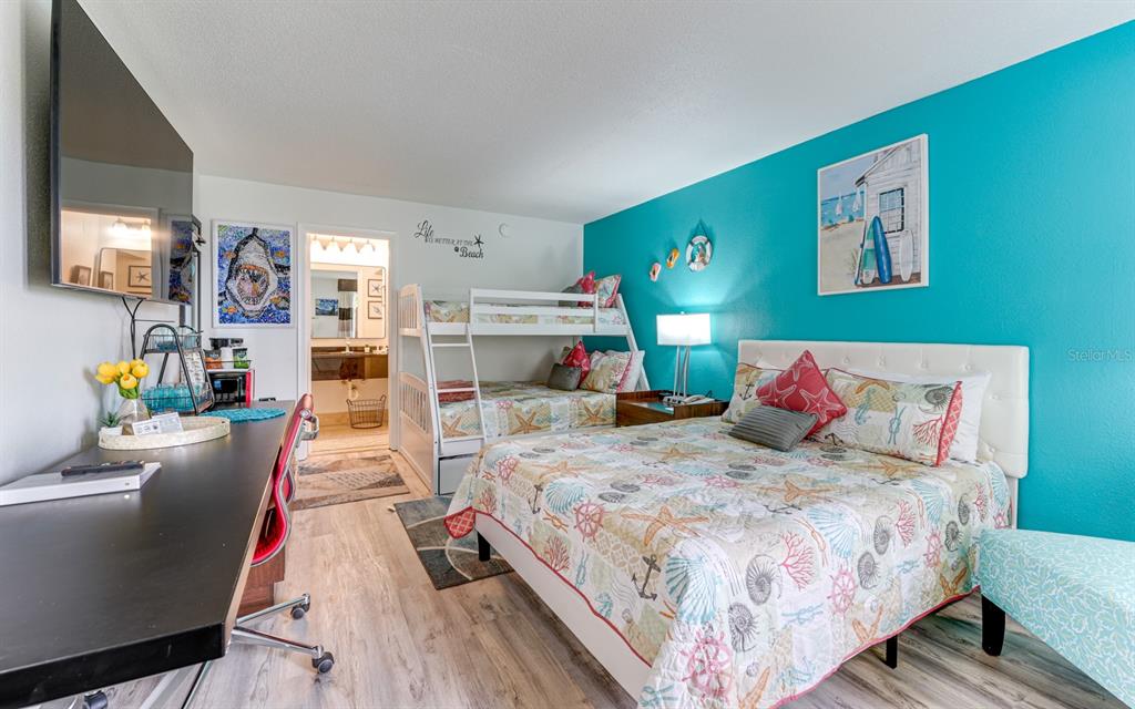 A bedroom features a queen bed, bunk beds, a desk, and a bright teal wall — 7150 N TAMIAMI TRAIL UNIT S-612, SARASOTA, FL