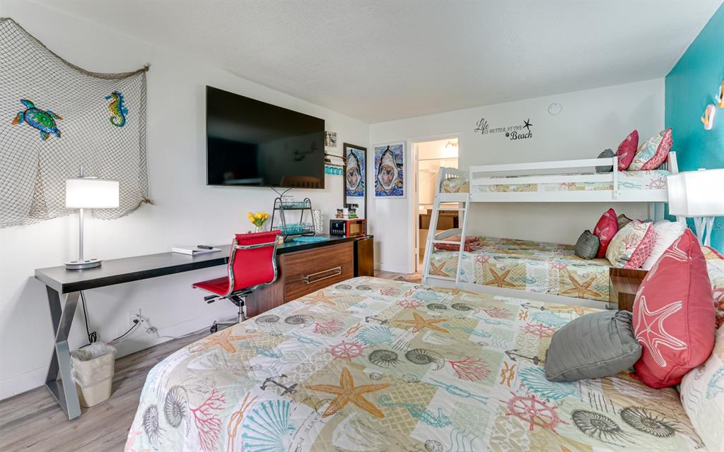A bedroom features a queen bed, bunk beds, a desk with a red chair, and television — 7150 N TAMIAMI TRAIL UNIT S-612, SARASOTA, FL