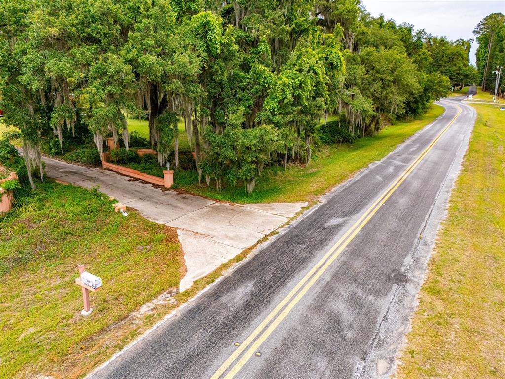 An aerial view shows a concrete driveway entrance leading to a wooded property from a road — 8845 NW 130TH STREET, REDDICK, FL