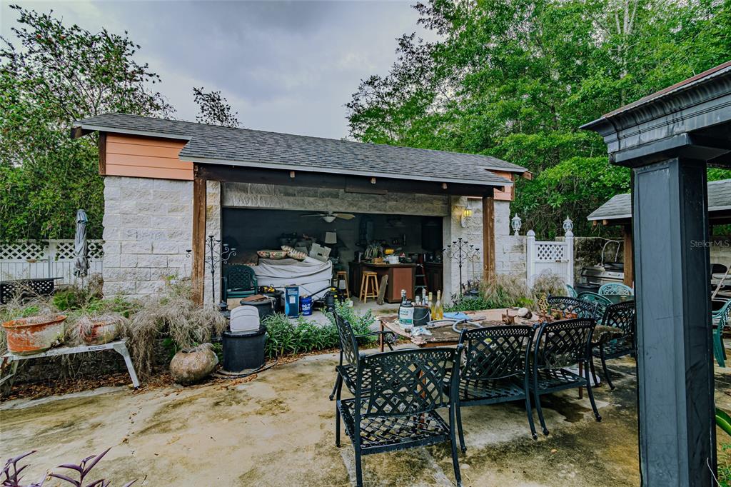 A patio with a dining set sits in front of an open-air stone garage — 8845 NW 130TH STREET, REDDICK, FL