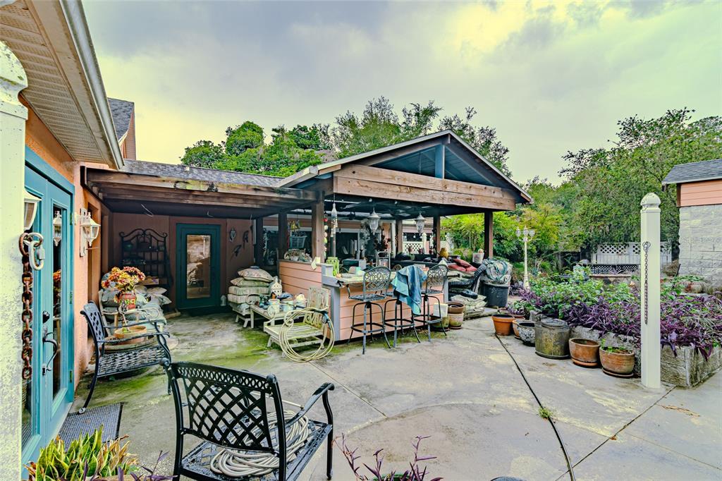 A covered outdoor patio features a bar, seating area, and potted plants on a concrete slab — 8845 NW 130TH STREET, REDDICK, FL