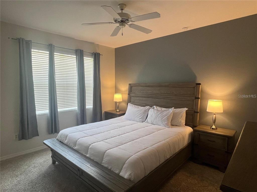 A bedroom features a wooden bed frame, two nightstands with lamps, and gray curtains — 326 CHELSEA DRIVE, DAVENPORT, FL