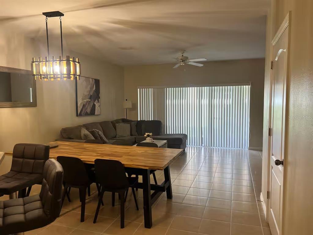 A dining area with a wooden table leads into a living room with a sectional sofa — 326 CHELSEA DRIVE, DAVENPORT, FL