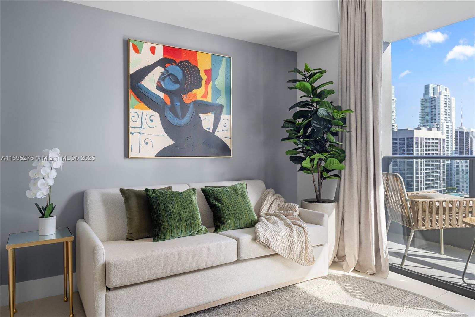 A living room features a beige sofa, abstract wall art, and a balcony with city views — 159 NE 6TH ST # 2414, Miami FL 33132, MIAMI, FL