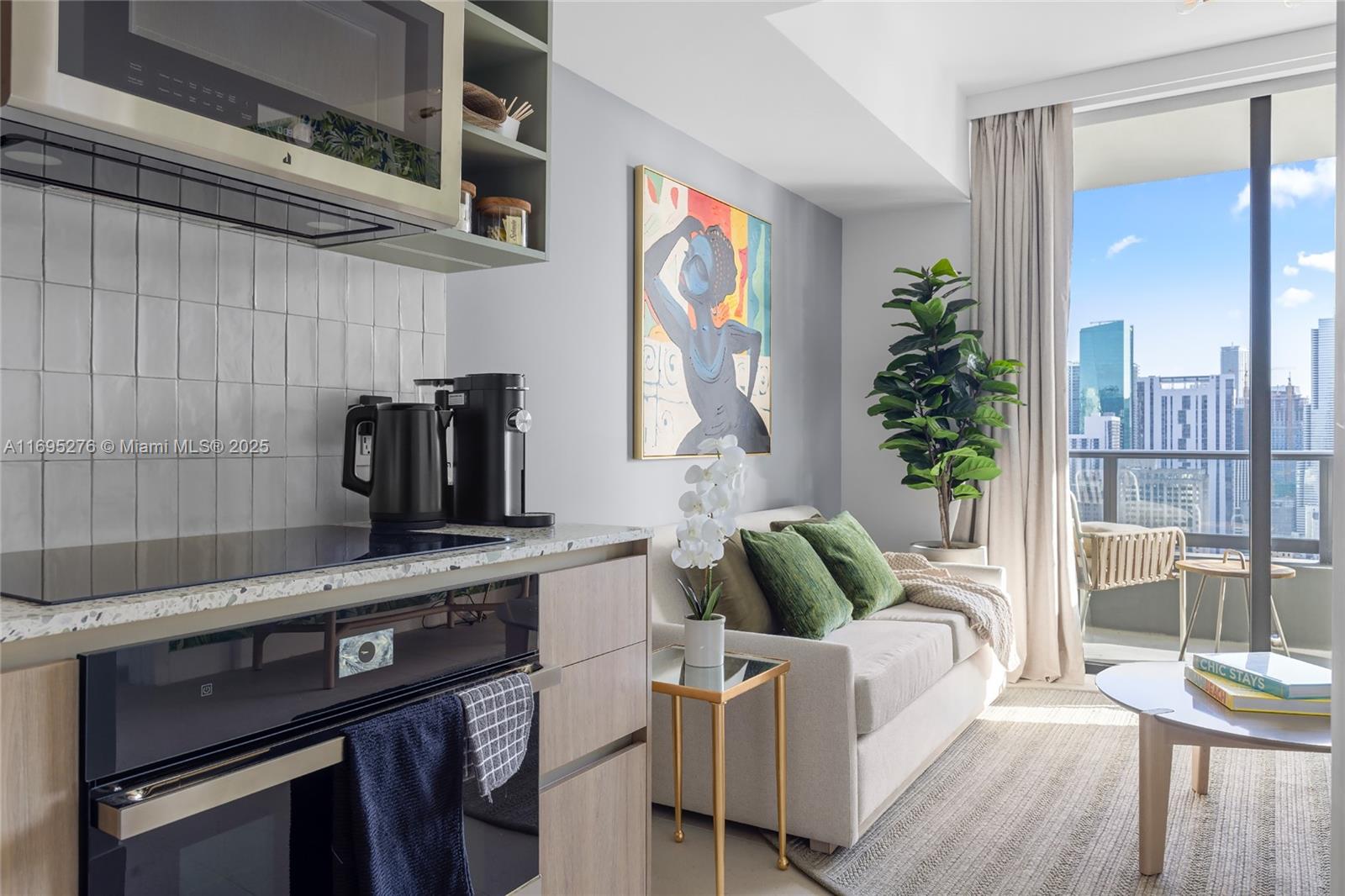 A modern studio apartment features a compact kitchen, a small sofa, and a balcony view — 159 NE 6TH ST # 2414, Miami FL 33132, MIAMI, FL