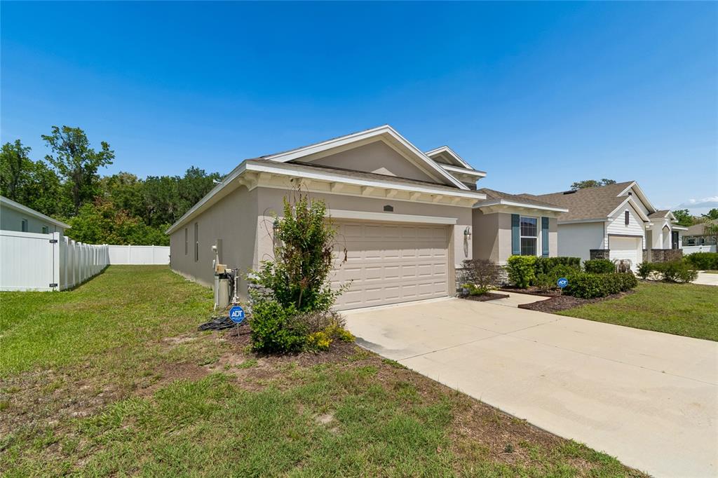 A tan single-story house with a two-car garage and a white vinyl fence — 35977 MORSE WILLOW COURT, ZEPHYRHILLS, FL