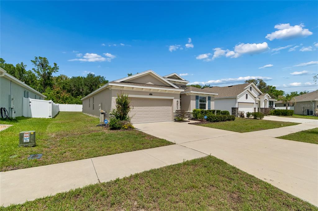 A single-story suburban house with a tan exterior, a two-car garage, and a concrete driveway — 35977 MORSE WILLOW COURT, ZEPHYRHILLS, FL