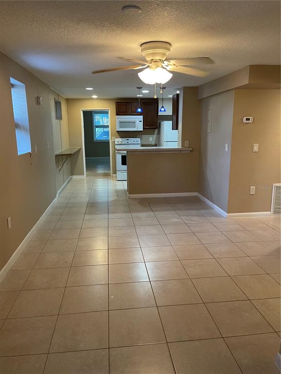 A room with tan walls and light-colored tile flooring features a ceiling fan and bathroom — 206 OSCEOLA AVENUE, EUSTIS, FL
