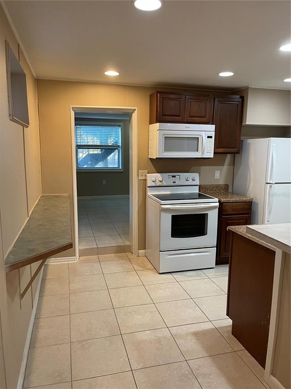 A kitchen features dark wood cabinets, white appliances, tile flooring, and a breakfast bar — 206 OSCEOLA AVENUE, EUSTIS, FL