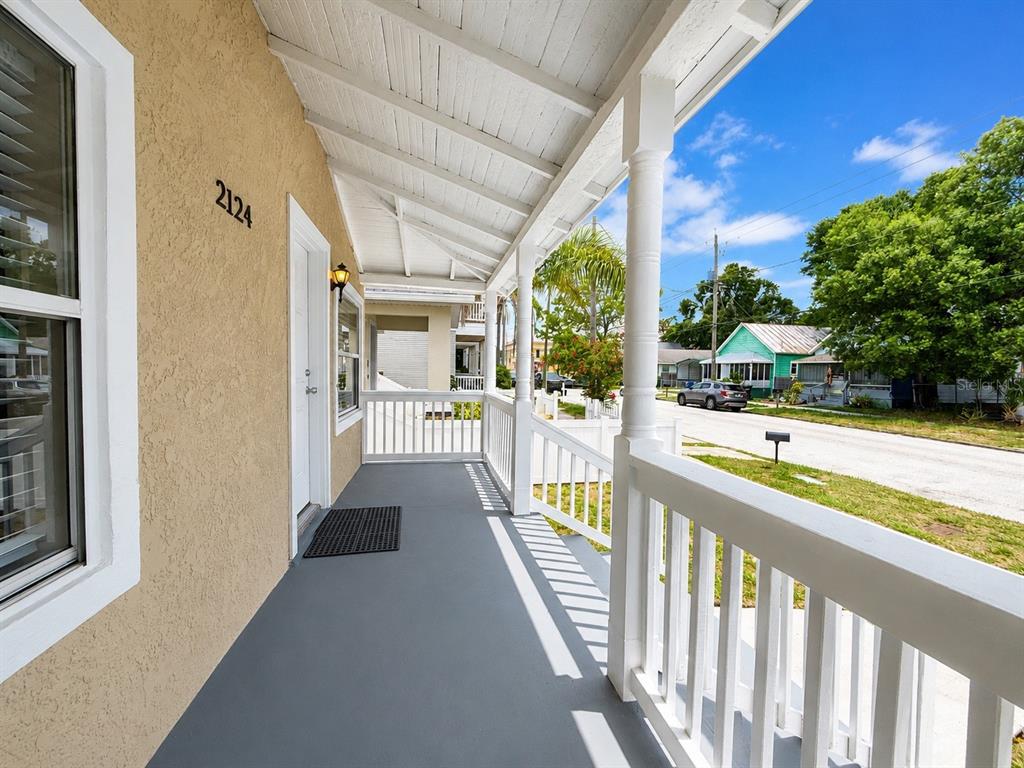 A covered front porch with a gray floor, white railings, and a tan exterior wall — 2124 W CHESTNUT STREET, TAMPA, FL