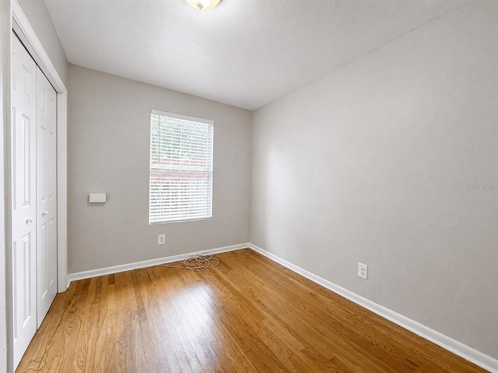 An empty bedroom features light gray walls, hardwood flooring, a window, and a white closet — 2124 W CHESTNUT STREET, TAMPA, FL