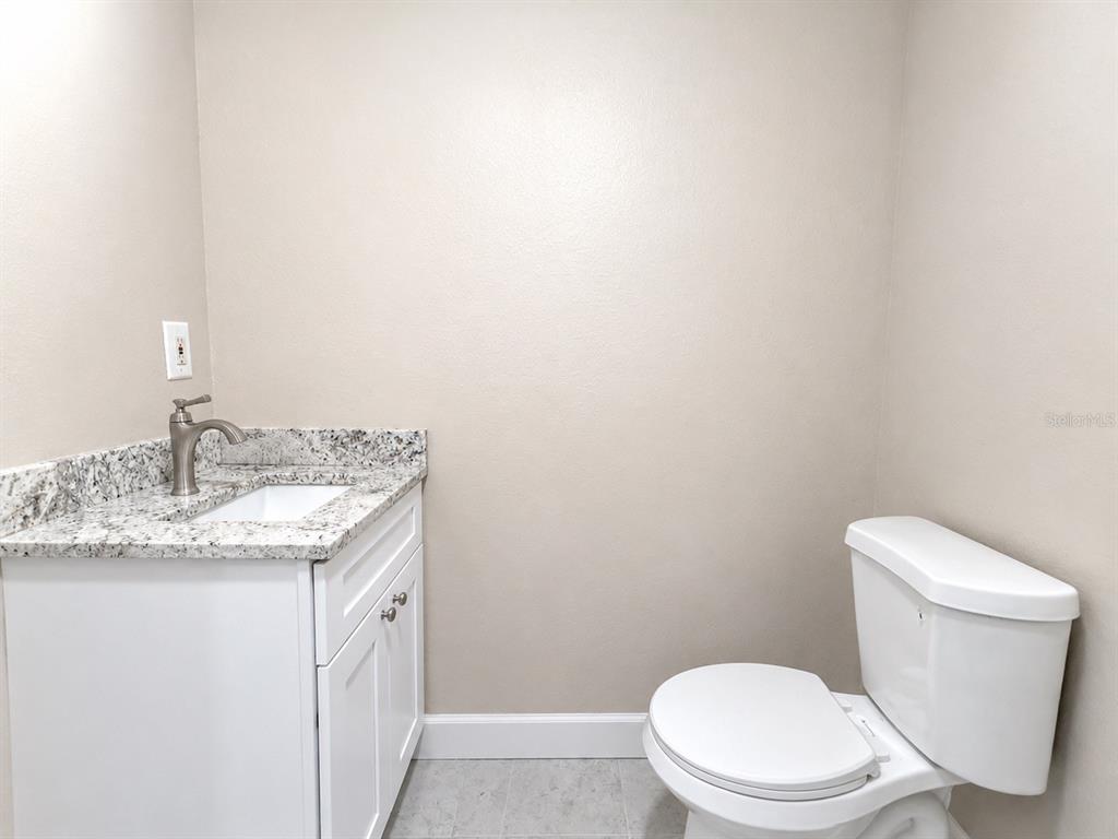 A small bathroom features a white vanity with a granite countertop and a white toilet — 2124 W CHESTNUT STREET, TAMPA, FL