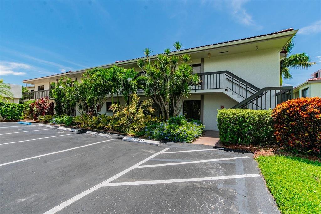 A two-story apartment building with a parking lot and tropical landscaping in the foreground — 6365 BAHIA DEL MAR BOULEVARD UNIT 210, ST PETERSBURG, FL
