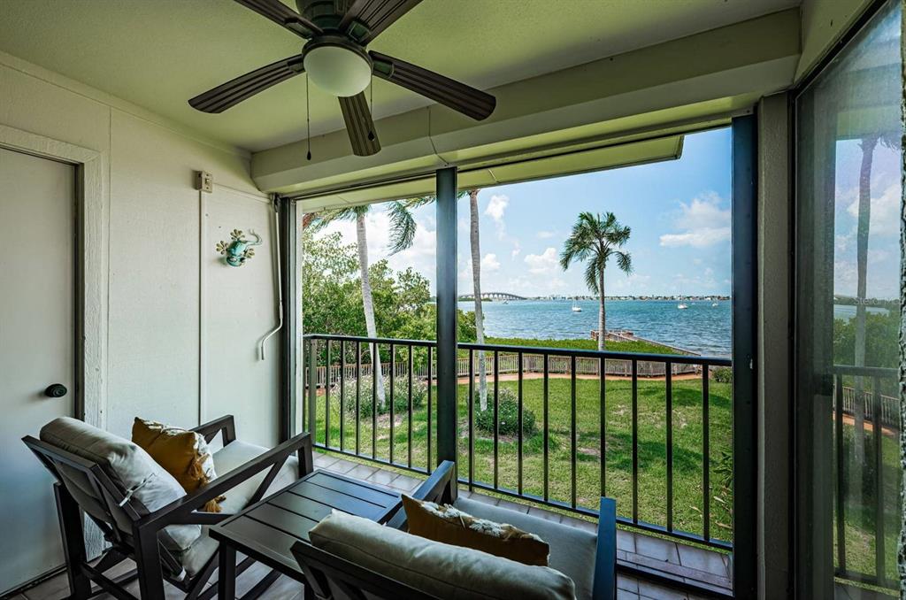A screened-in balcony features a ceiling fan, two chairs, and a view of the water — 6365 BAHIA DEL MAR BOULEVARD UNIT 210, ST PETERSBURG, FL