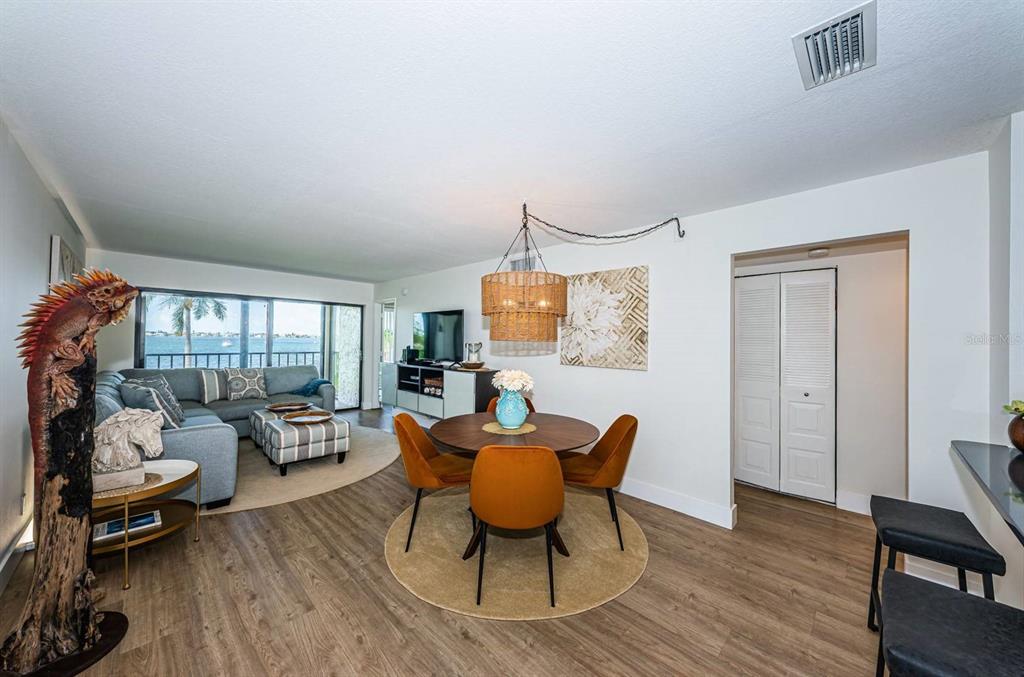 A living and dining area features wood-look flooring, a round table, and a water view — 6365 BAHIA DEL MAR BOULEVARD UNIT 210, ST PETERSBURG, FL