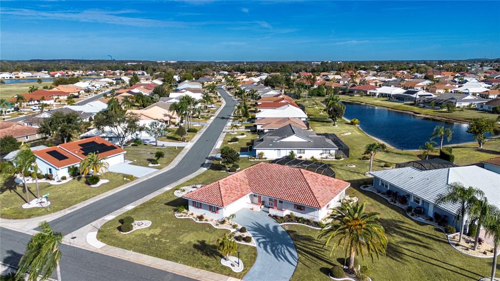 An aerial view shows a suburban neighborhood with single-family homes, a lake, and streets — 1853 WOLF LAUREL DRIVE, SUN CITY CENTER, FL