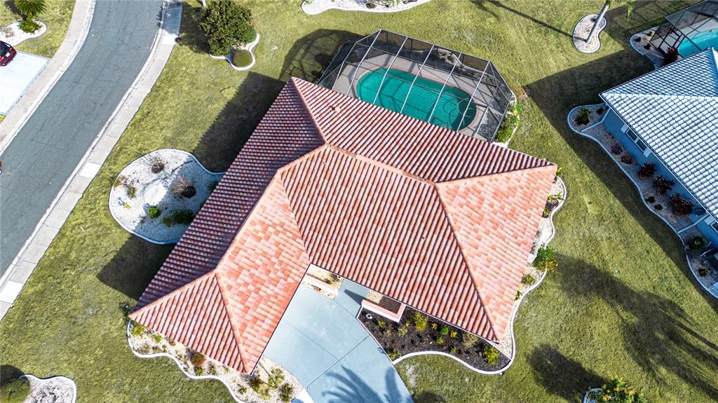 An aerial view shows a house with a tiled roof, a screened-in pool, and driveway — 1853 WOLF LAUREL DRIVE, SUN CITY CENTER, FL