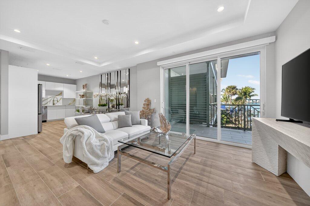 A modern living room with light wood floors, a white sofa, and a glass balcony door — 41 SW Seminole Street # 304, Stuart FL 34994, STUART, FL