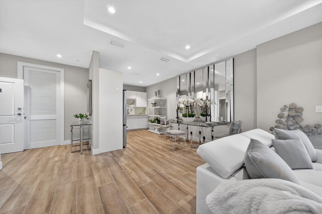 A modern living room and dining area with light wood floors and mirrored wall panels — 41 SW Seminole Street # 304, Stuart FL 34994, STUART, FL