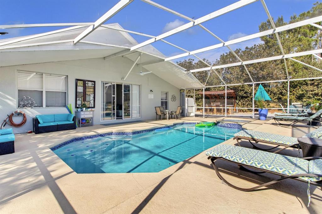 A screened-in patio features a swimming pool, lounge chairs, and outdoor seating — 256 CORK WAY, DAVENPORT, FL