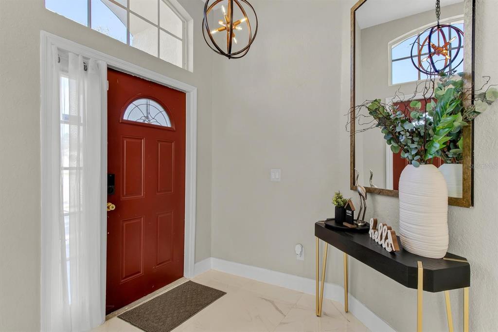 An entryway features a red front door, a console table, and a large wall mirror — 256 CORK WAY, DAVENPORT, FL