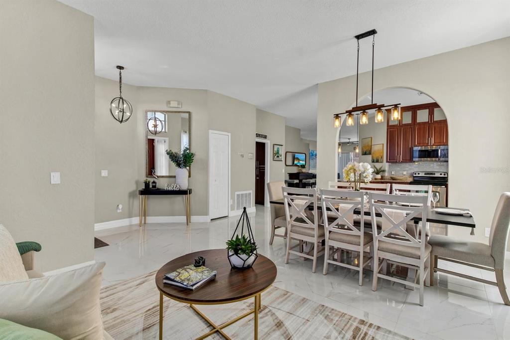 A dining area and living room with white tile floors, neutral walls, and modern lighting — 256 CORK WAY, DAVENPORT, FL