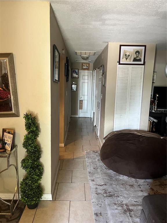 A hallway with tile flooring leads to a closed door, flanked by walls with framed pictures — 3104 E CHELSEA STREET, TAMPA, FL
